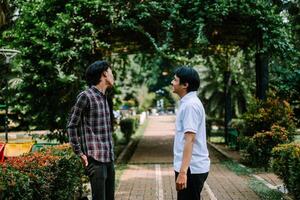 Two Southeast Asian men engaged in a lively conversation at a city square. photo