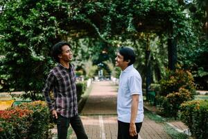Two Southeast Asian men engaged in a lively conversation at a city square. photo