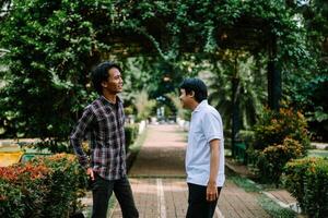 Two Southeast Asian men engaged in a lively conversation at a city square. photo