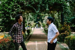 Two Southeast Asian men engaged in a lively conversation at a city square. photo