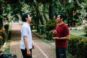 Two Southeast Asian men engaged in a lively conversation at a city square. photo