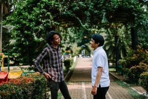 Two Southeast Asian men engaged in a lively conversation at a city square. photo