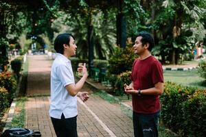 Two Southeast Asian men engaged in a lively conversation at a city square. photo