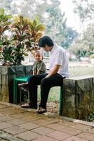 A father and his child sitting and chatting in a city square photo