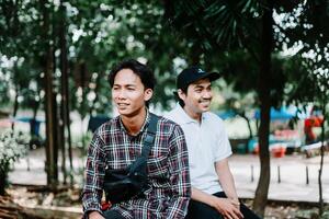 Two Southeast Asian men sitting in a city square, capturing a moment of relaxation and conversation photo