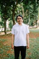 Southeast Asian man standing on an open grassy field in a city square, capturing a moment of calm and space. photo