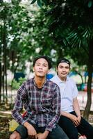 Two Southeast Asian men sitting in a city square, capturing a moment of relaxation and conversation photo