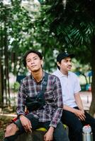 Two Southeast Asian men sitting in a city square, capturing a moment of relaxation and conversation photo