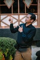 Southeast Asian man dressed neatly, pointing to the right with focus photo