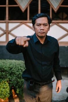 Southeast Asian man pointing forward with an intimidating expression. photo