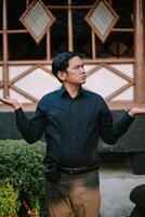 Southeast Asian man asking a question with a curious expression and engaged body language. photo