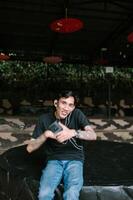 Southeast Asian tatoo man enjoying music through earphones, with a relaxed and content expression. Ideal for themes of leisure photo