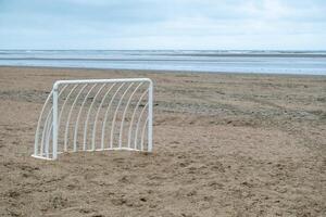 small metal soccer goal on a lonely beach photo