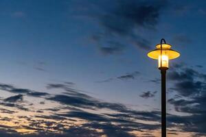 illuminated street lamp in front of a rainy autumn sky photo