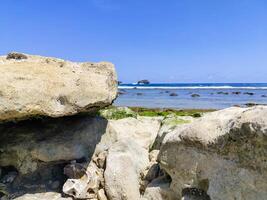 Rocks on the shoreline with a blue sky. photo
