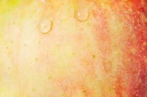 Red and yellow apple texture with two water drops. Apple as a background. photo