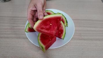 A person holding a slice of fresh watermelon on a plate, perfect for summer picnics and Independence Day barbecues video