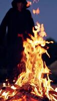 Man in cassocks by the fire. Monk in brown cloaks of the order of St. Francis by the fire Vertical video