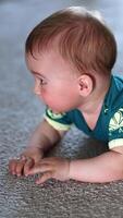 Little child banging his hands over the floor happily. Beautiful kid lies on a carpet looking up with interest. Vertical video