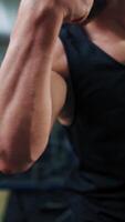Strong athletic man on mirror background in gym. Muscular man shows his trained biceps on arms while looking at his reflection in the mirror. Vertical video