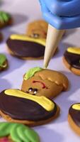 Cookies production in confectionary factory. Hands in gloves decorate biscuits in the shape of mushrooms with creamy decorations. Close up. Vertical video