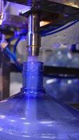 Water is poured into big blue bottle and overflows it. Filled bottles are covered with plastic white corks. Close up. Vertical video