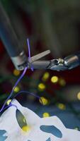 Tiny forceps of Da Vinci system tying a knot on a thread. Fastening the thread on the paper snowflake by robotic arms of Da Vinci surgical system. Close up. Vertical video