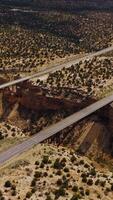 Huge crack in the rocks of desert in Utah, USA. Bridges connecting the sides of a split for transport to pass. Aerial view. Vertical video