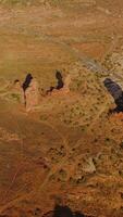 Few lonely little rocks among the deserted landscape. Highway crossing the scenery with some cars going by. Top view. Vertical video