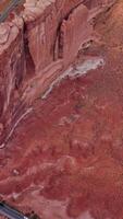 Stunning beautiful flat rock located in the middle of desert. Drone flight over the rounded peak mount and road passing below it. Top view. Vertical video
