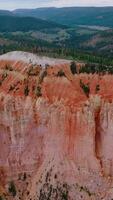 Stunning huge rock of coral color in Bryce National Park. Mountains overgrown with pine forest at backdrop. Aerial view. Vertical video