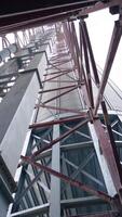 Pipes and supports at the grain-drying complex. High steel constructions at the backdrop of sky. View on the structure from below. Vertical video