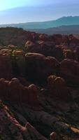 Rounded red rocks in Utah, USA in the rays of bright sun. Arches National Park at the backdrop of blue skies. Aerial view. Vertical video