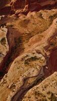 Unusual oddly-shaped red rocks of American canyons in Utah. Descending over a big rock with tiny greenery on top. Vertical video