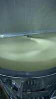Big cistern with automatic mixing system inside. Beating the butter in automatic mixer tank. Butter production at milk factory close up. Vertical video