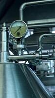 Steel shiny tubes with sensors and valves interlinking with each other. Complicated equipment for dairy food production. Vertical video