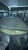 Three silver tanks for mixing milk products. Dairy production at the modern food factory. Steel tanks with open lids standing in row. Vertical video