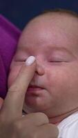 Mother is touching gently baby's forehead, nose and cheeks. Adorable toddler is sleeping tightly and doesn't wake to wake up. Close up. Vertical video
