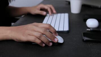 woman looking for educational references with her hand scrolling through a computer mouse video