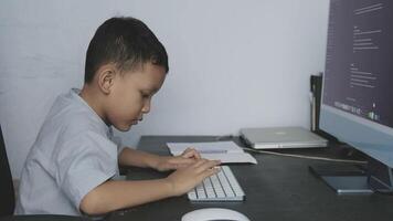 a boy is learning to do his schoolwork in front of a computer by typing his keyboard video
