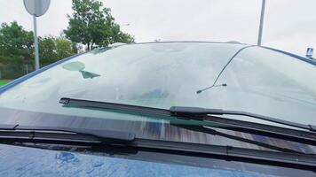 Close-up of car windshield wipers clearing rainwater on rainy day. Safety driving in wet conditions video