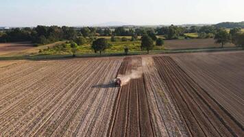 Red tractor working in agricultural field, cultivating and plowing dry soil, aerial view. Agribusiness concept. Small farming concept video