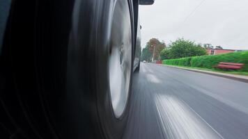 Car driving on wet asphalt road at street. Close up of vehicle wheel with tire in motion on rainy day video