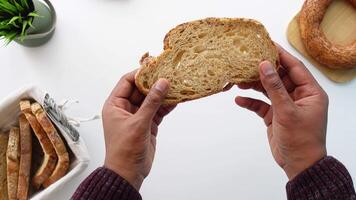 A Pair of Hands Gently Holding a Slice of Whole Grain Bread, with a Basket in the Background video