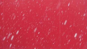 A mesmerizing snow gently falls against a bright red background, creating a winter scene video
