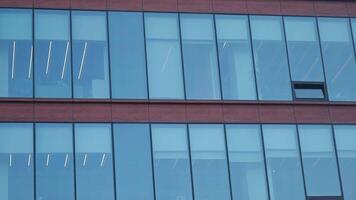 A modern office building facade with large glass windows that reflect its surroundings video