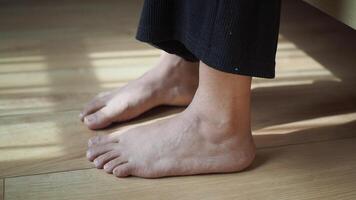 Bare feet gently resting on a smooth wooden floor illuminated by warm, natural light video