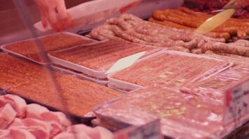Womans hands arranging minced meat in plastic containers in a window shop. video