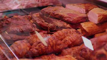 Window case see-through close up set of smoked meat goods for sale. video