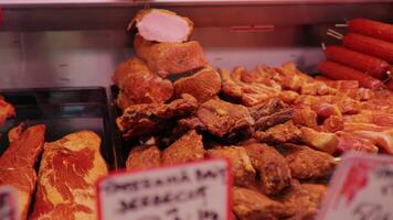 Meat department worker adding smoked chuncks of beef rib eye in shop window. video